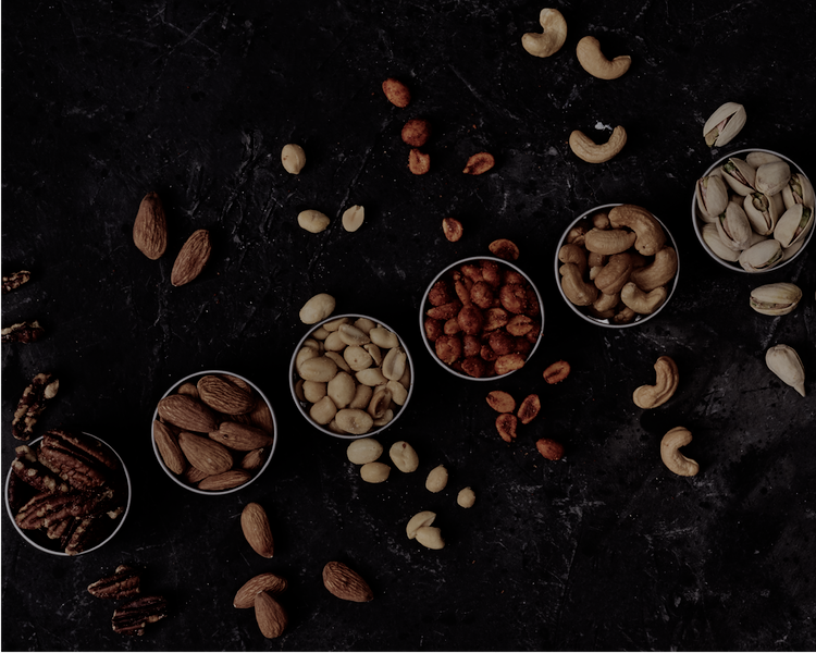 A slate board with pecans, almonds, peanuts, cashews and pistachios
